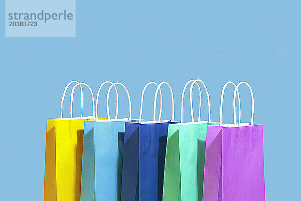 Multi colored shopping bags against blue background