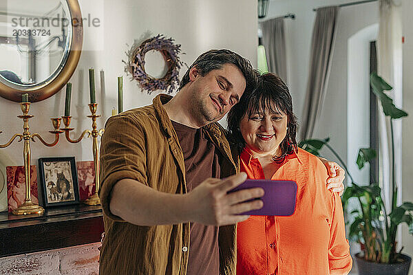 Smiling man taking selfie with mother at home