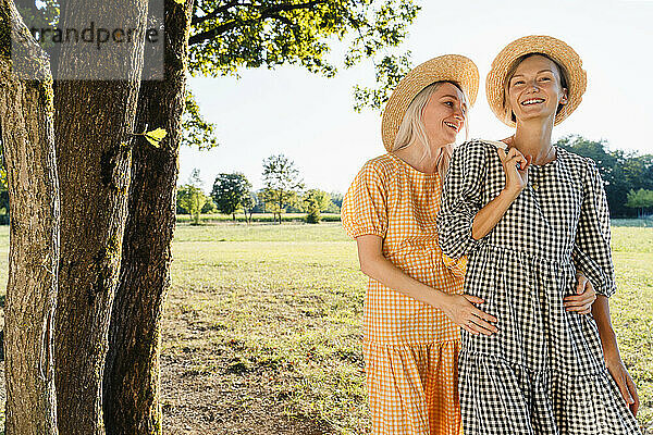 Happy friends wearing hats standing in park