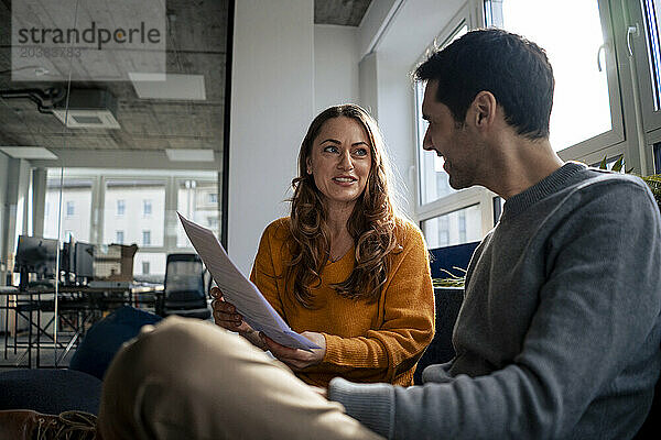 Smiling mature businesswoman discussing over document in office