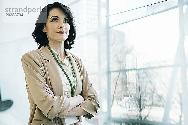 Confident businesswoman standing with arms crossed at office