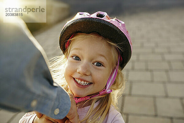 Happy girl wearing sports helmet on footpath