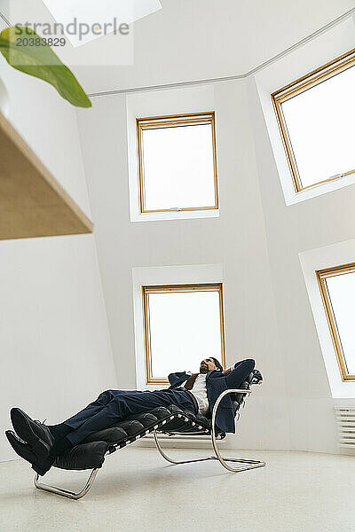 Businessman relaxing on lounge chair in office