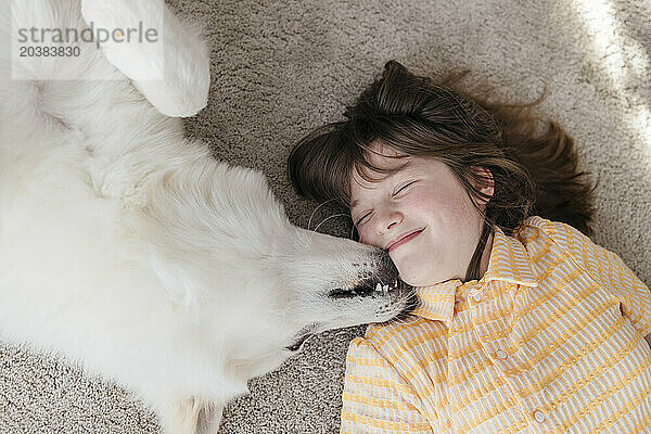 Cute girl and dog lying on carpet at home