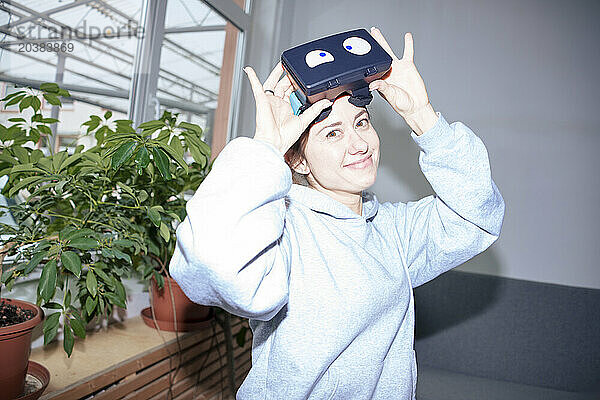 Smiling woman wearing virtual reality headset at home