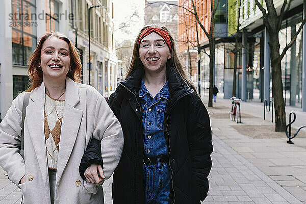 Happy friends walking together on street in London city