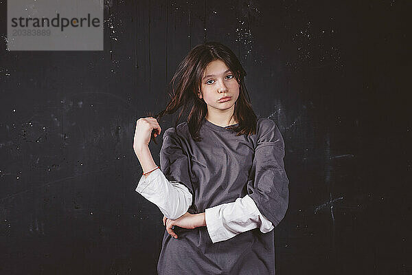 Sad girl holding hair standing in front of black background