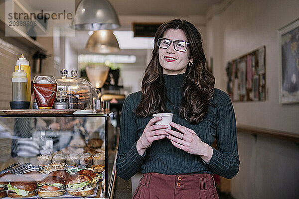 Smiling businesswoman standing near food display in cafe