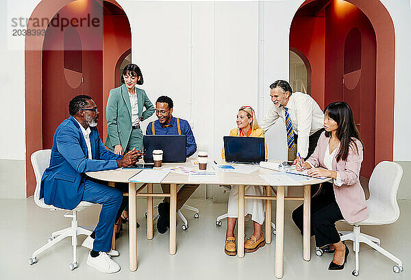 Corporate business colleagues working together at desk in office