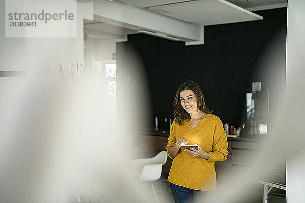 Smiling businesswoman with tablet PC in creative office