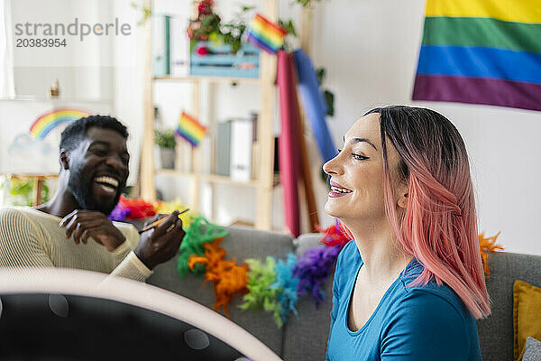 Smiling woman with dyed hair near non-binary friend at home