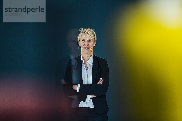 Smiling mature businesswoman standing with arms crossed