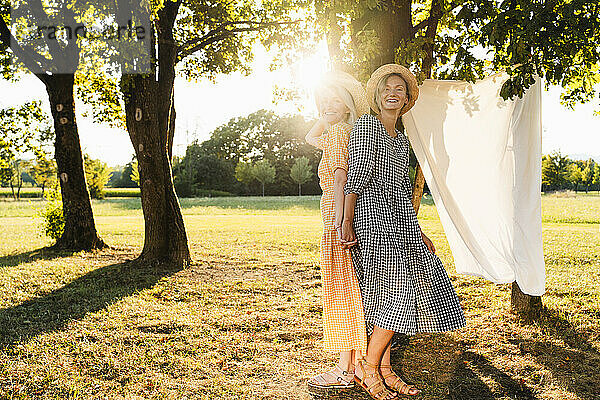 Women standing back to back in park