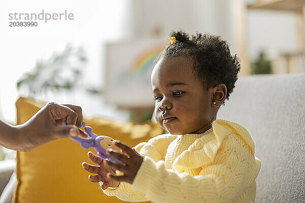 Cute girl taking toy from mother at home