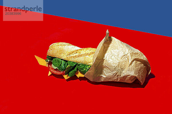 Cheese sandwich wrapped in paper on red background