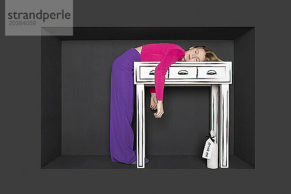 Teenage girl leaning on table by black background