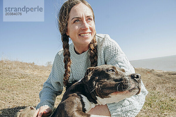 Happy woman with dog on hill at sunny day