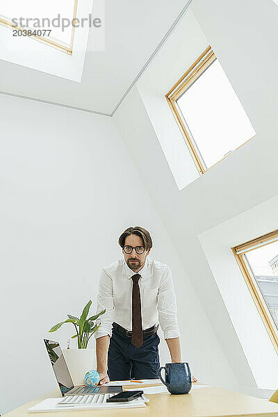 Businessman leaning on desk at office