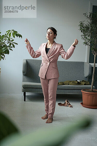 Businesswoman with eyes closed meditating in living room at home