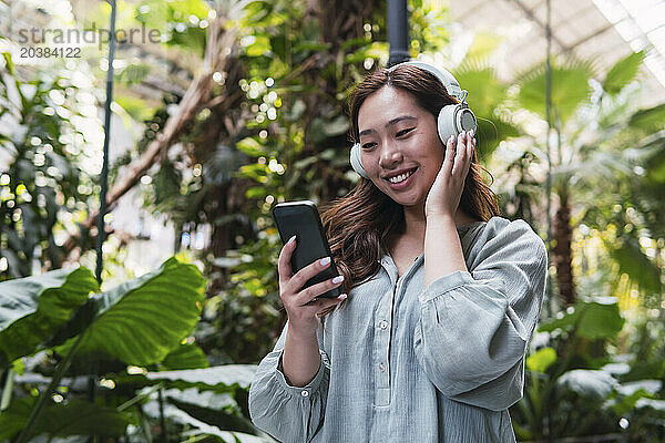 Young woman enjoying listening to music through wireless headphones