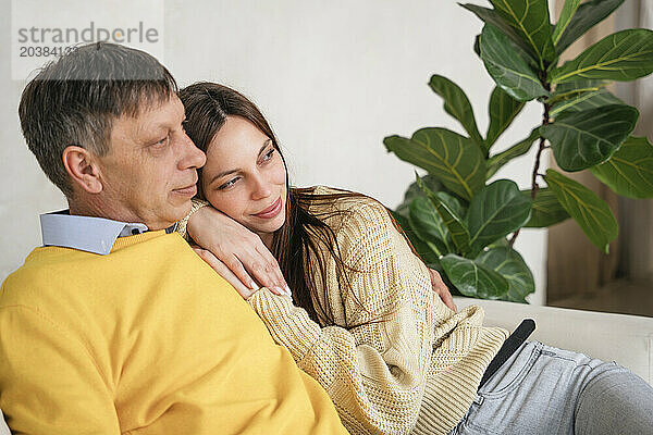 Thoughtful father and daughter on sofa at home