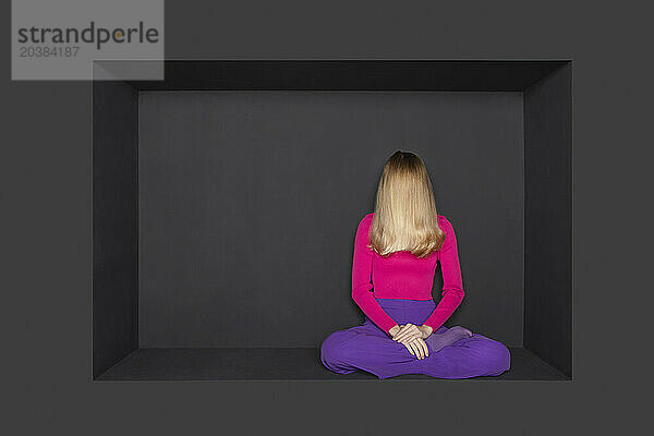 Blond girl sitting in alcove over black background