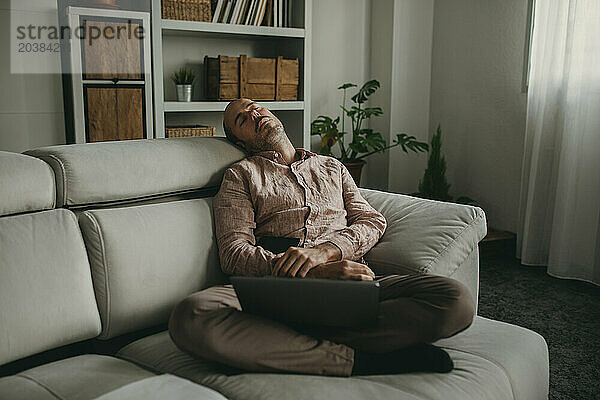 Tired freelancer taking nap on sofa at home office