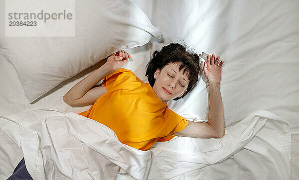 Woman in yellow t-shirt sleeping on bed at home
