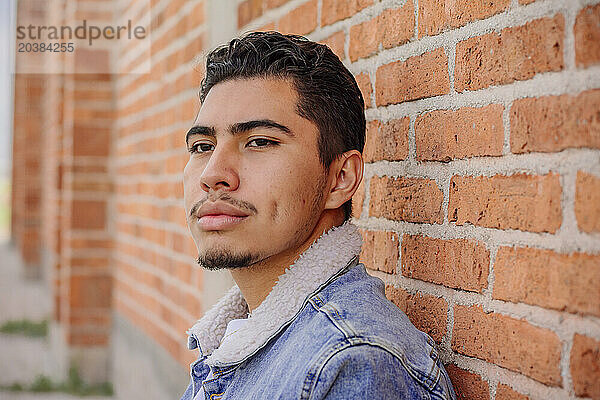 Thoughtful young man by brick wall