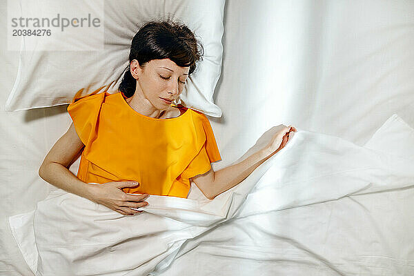 Woman in yellow t-shirt sleeping on bed at home