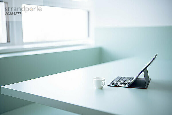 Tablet PC attached with keyboard near coffee cup on desk