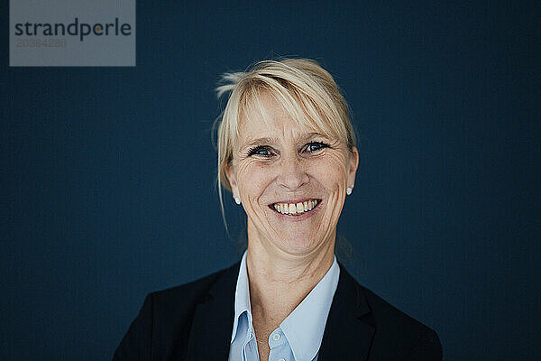 Happy businesswoman against navy blue background