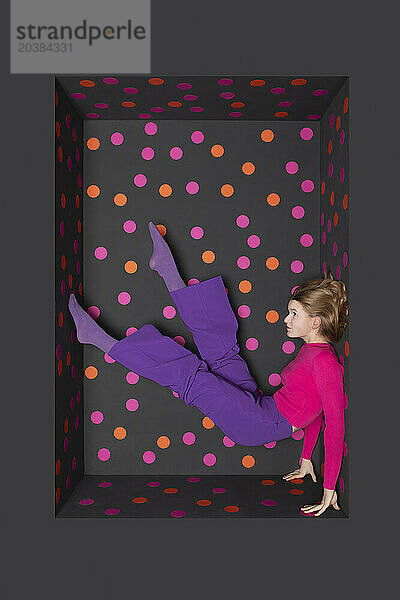 Teenage girl with legs up over black background with colored dots