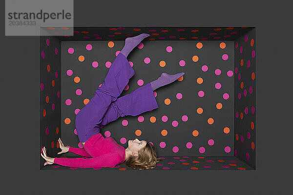Teenager with legs up over black background with colored dots