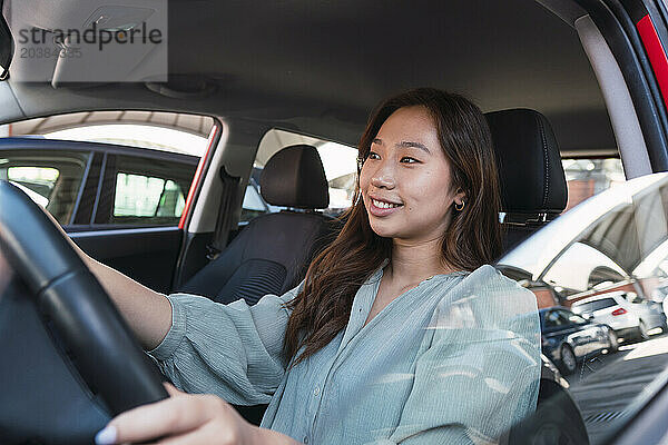 Smiling young woman driving car