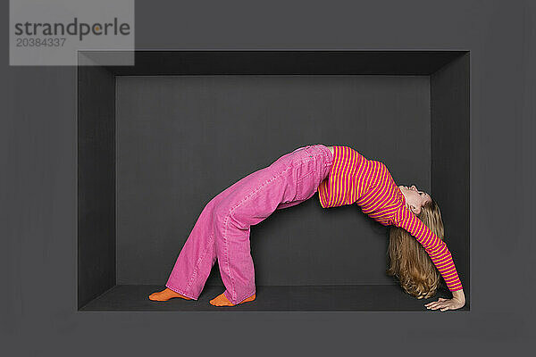 Teenage girl bending backward against black backward