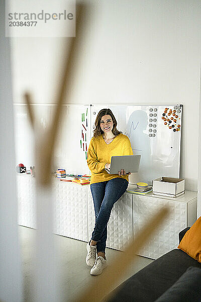 Happy businesswoman with laptop in front of whiteboard