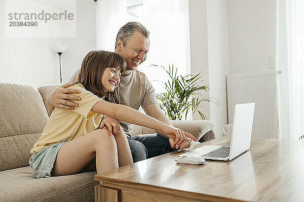 Happy father and daughter watching movie and having fun at home