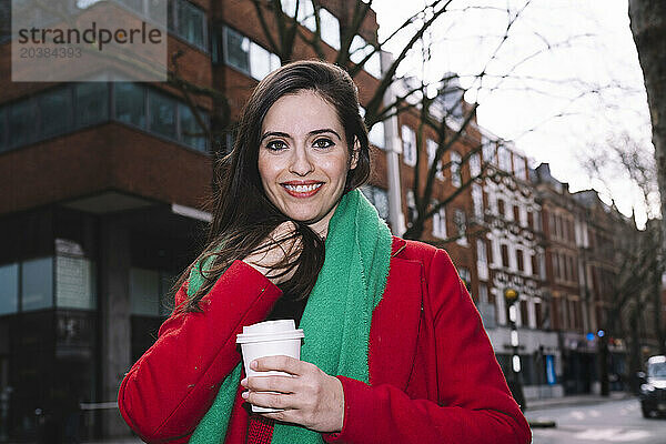 Smiling woman with disposable coffee cup in city