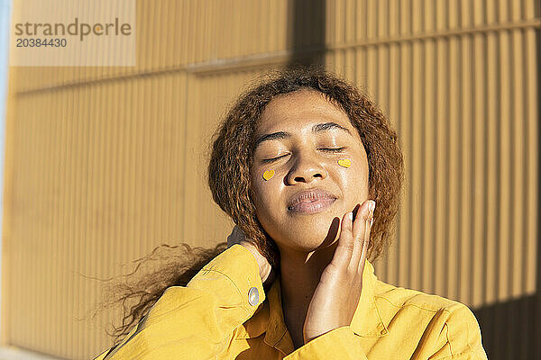 Woman with yellow heart shape stickers on cheeks