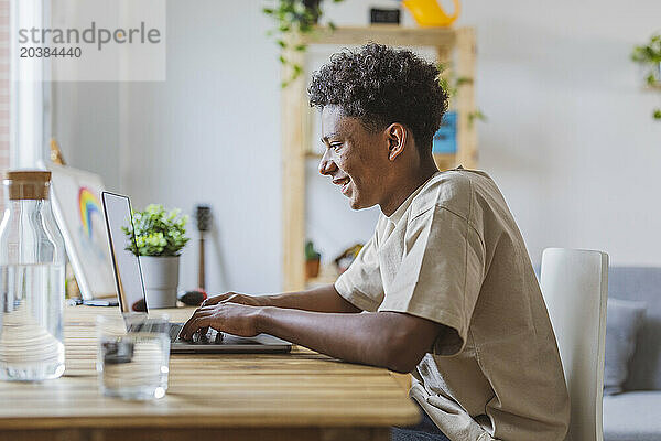 Smiling teenage boy using laptop at home