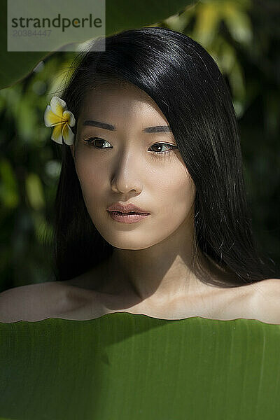 Beautiful young woman near banana leaves