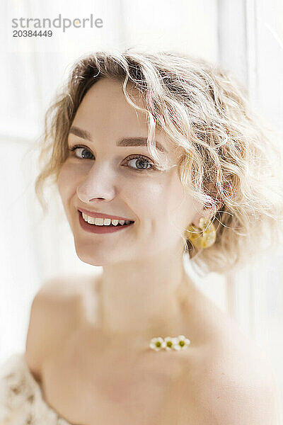 Smiling blond woman with flowers on clavicle