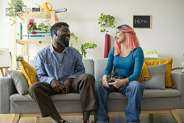 Happy friends sitting on sofa in living room at home