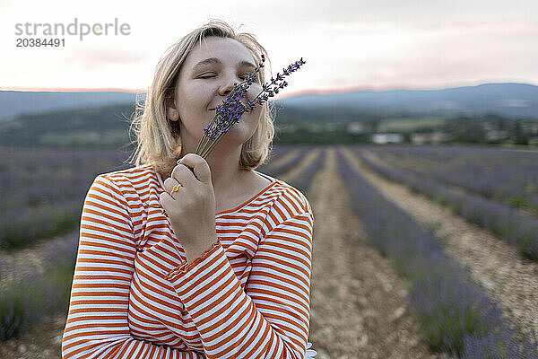 Woman with eyes closed smelling lavender at field