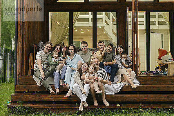 Happy friends and family sitting together at porch of house