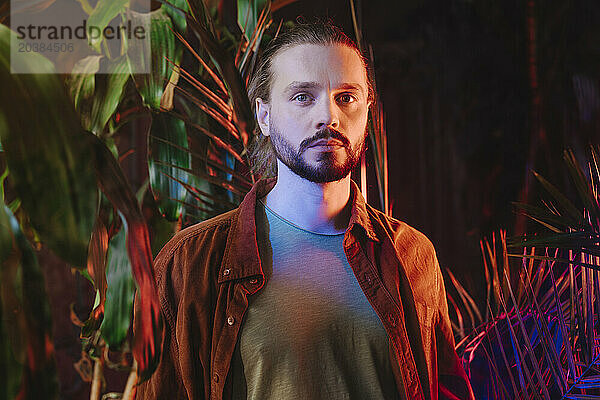 Man standing near plants in neon lights