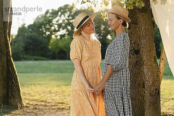 Women wearing hats and holding hands in park