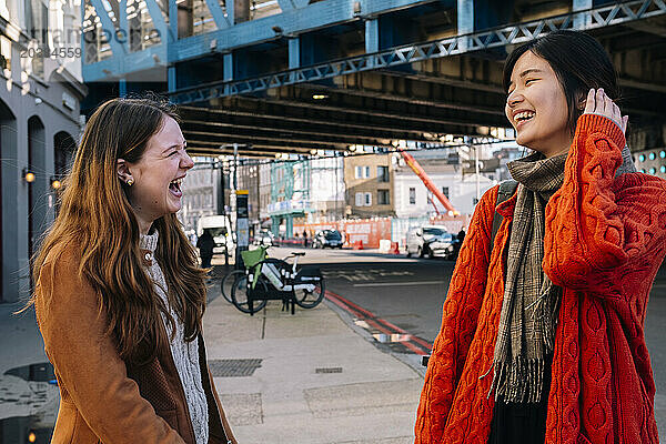 Cheerful young sisters having fun on street