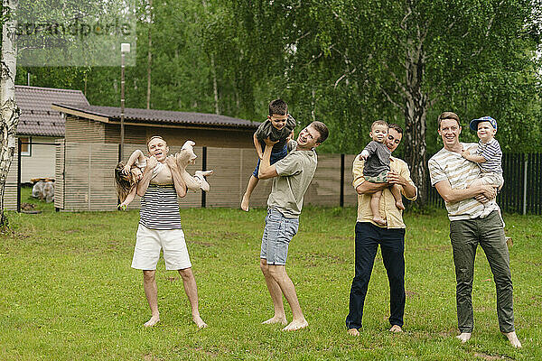 Happy fathers carrying children playing in back yard on weekend